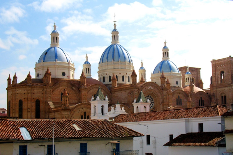 three blue church spires above buildings in Cuenca, Ecuador